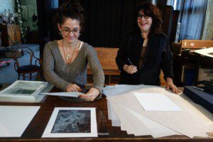Jenny Bagert assists Josephine Sacbo while signing prints in her studio